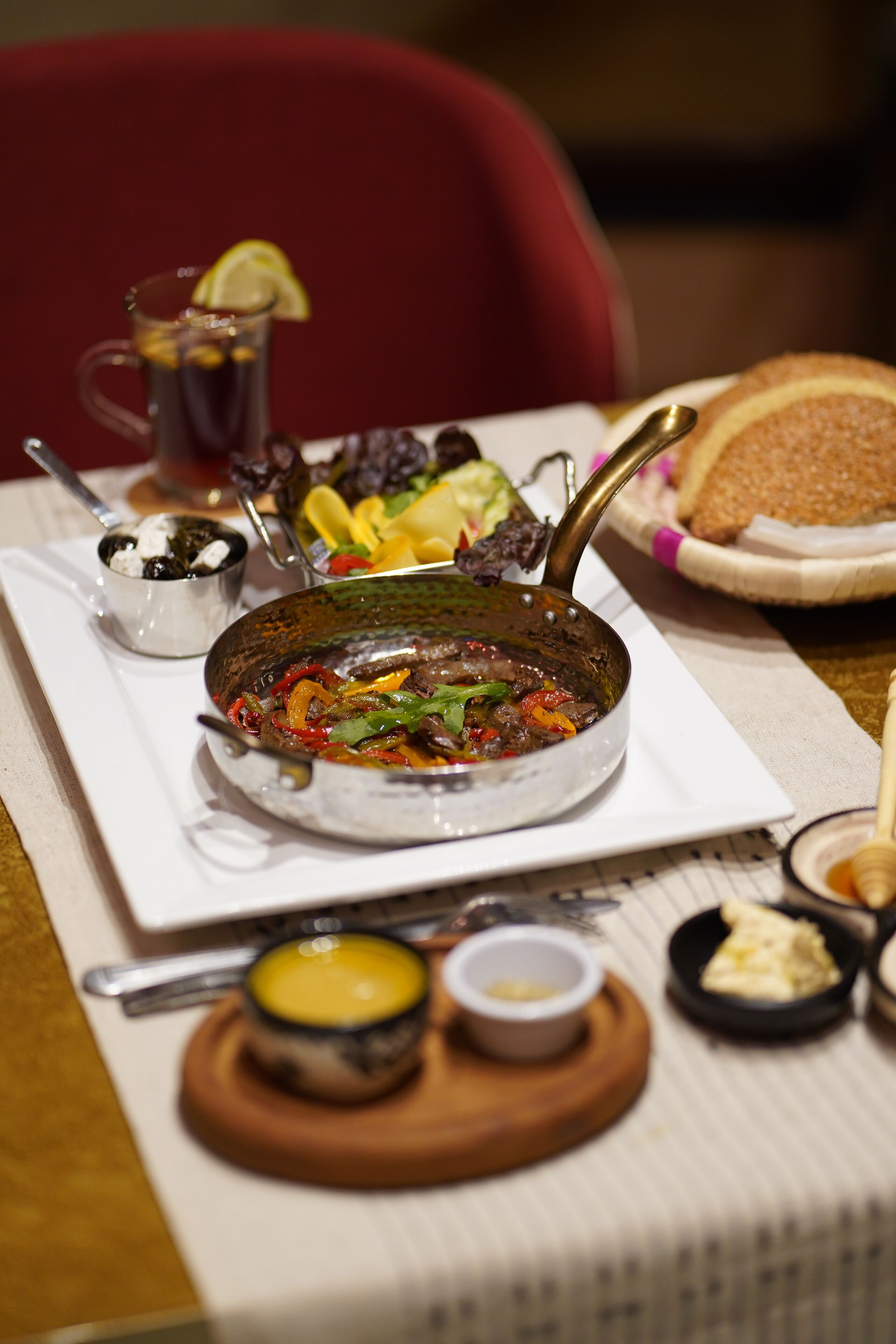A dining table with a variety of dishes, including a pan of stew, bread, and small bowls of condiments.
