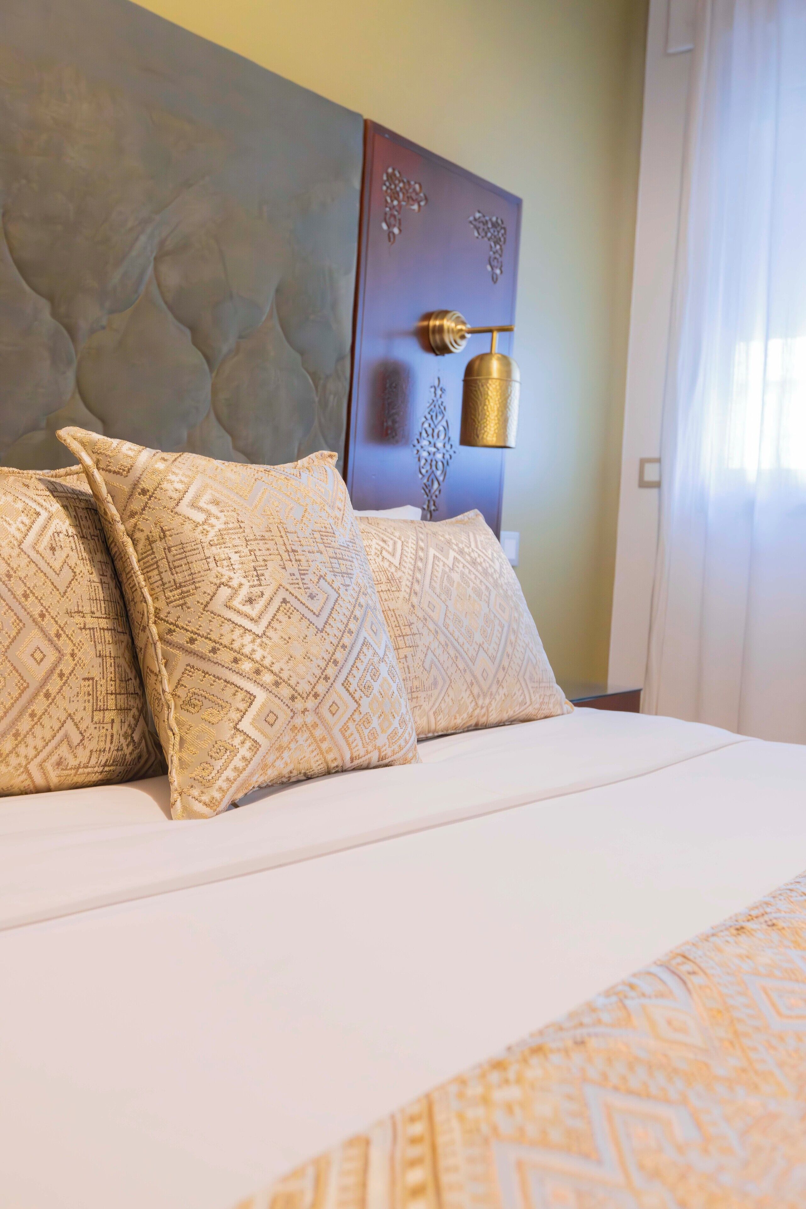 Una cama con almohadas estampadas y un cabecero decorativo.