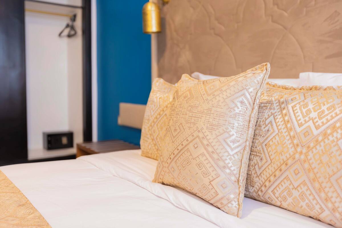 Una cama bien hecha con almohadillas estampadas y un cabecero.