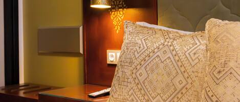 Una habitación de hotel con una cama bien hecha, una lámpara de noche y una lámpara de pared.