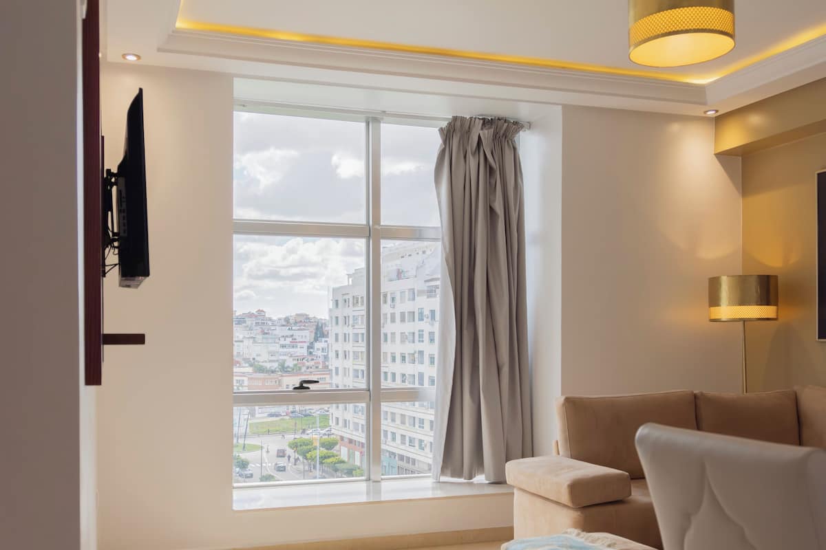 Una sala de estar moderna con un amplio ventanal, un sofá, un sillón y una lámpara en el techo.