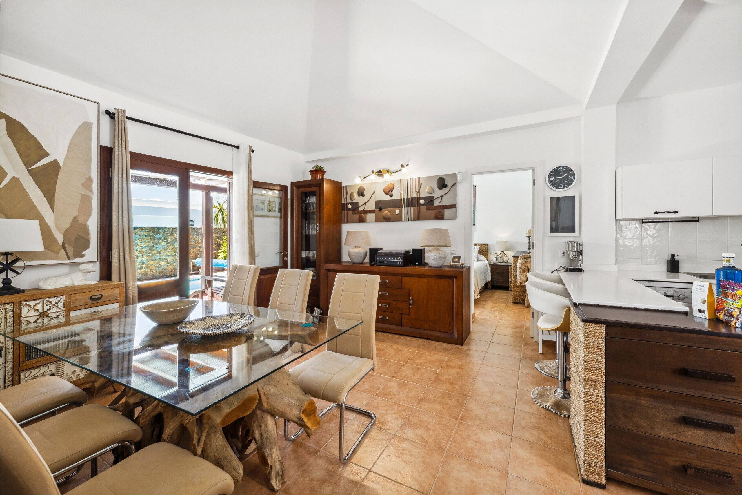 Een moderne keuken met een glazen eettafel, houten kasten en uitzicht op de omgeving.