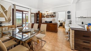 Una cocina moderna con una mesa de comedor de vidrio, armarios de madera y vistas al exterior.