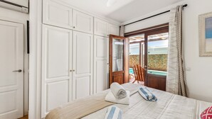 Un dormitorio con cama, armario y puerta que da a un balcón con vistas.