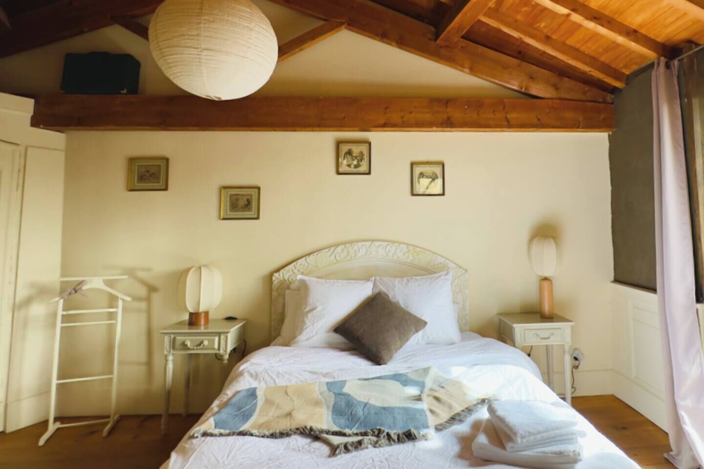 Une chambre à coucher comprenant un lit, une table de chevet, une commode, une lampe suspendue, une armoire et un escabeau.