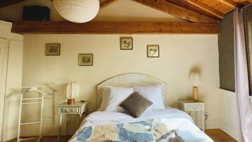 Une chambre à coucher comprenant un lit, une table de chevet, une commode, une lampe suspendue, une armoire et un escabeau.
