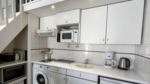 A compact kitchen with a microwave, sink, and coffee maker.
