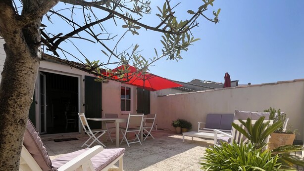 A patio with outdoor furniture, a red umbrella, and potted plants.