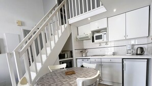 A compact kitchen with white cabinets, a microwave, a coffee maker, and a dishwasher.