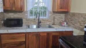 Una cocina con armarios de madera, microondas, pileta y estufa.