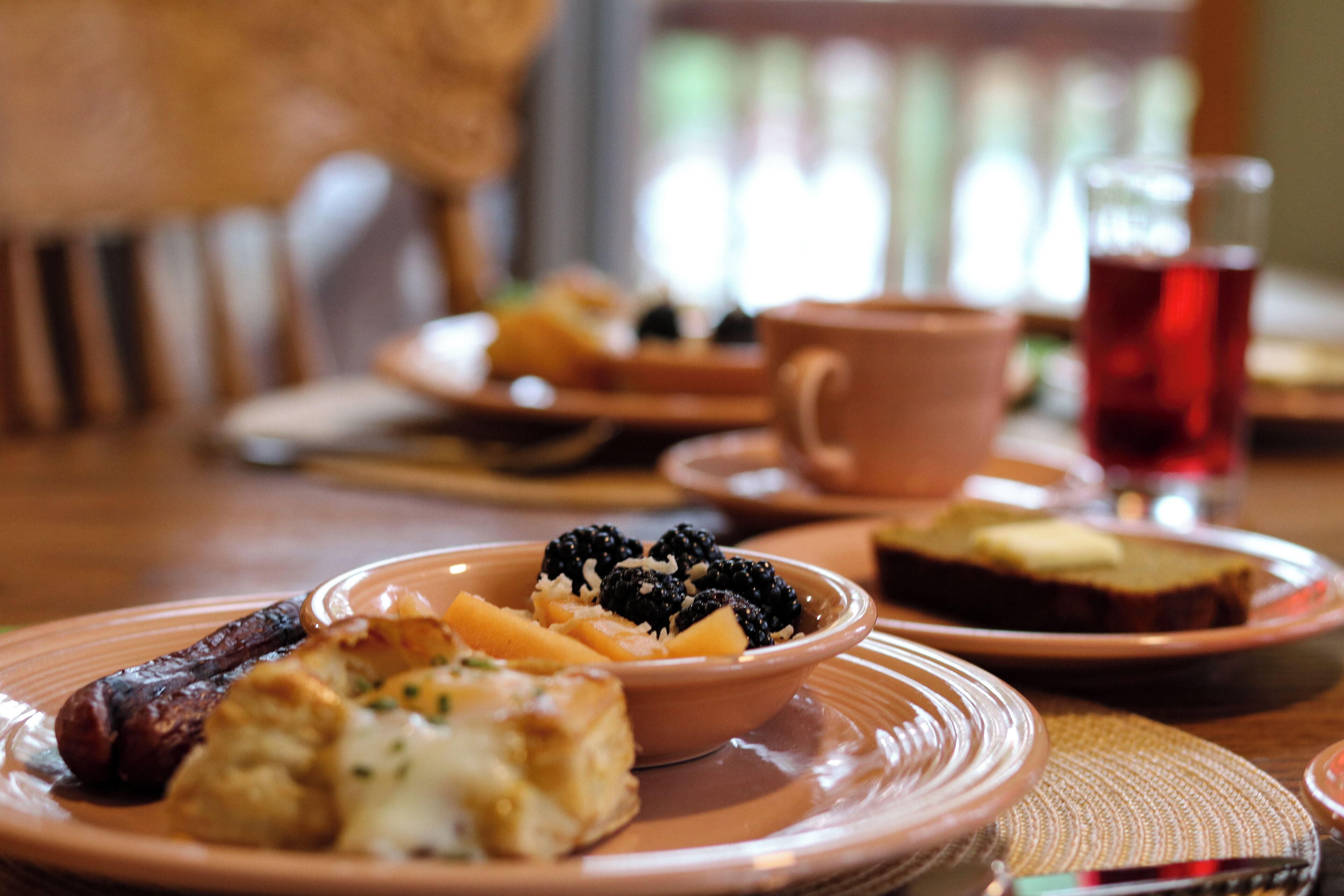 A dining table with plates of food, including a bowl of fruit and a cup of tea.