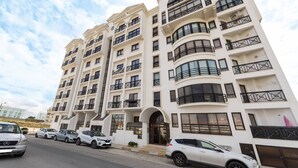 Um edifício residencial de vários andares com varandas e entrada protegida por portão.