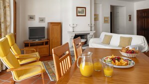 Uma sala de jantar com uma mesa de madeira, cadeiras amarelas, uma televisão e uma lareira.