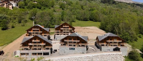 A mountain lodge with multiple wooden buildings, a stone pathway, and a view of the surrounding mountains.