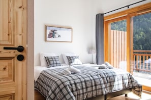 Un dormitorio con una cama, un cuadro en la pared y vistas a un balcón con barandilla.
