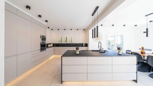 A modern kitchen with a large island, built-in appliances, and a dining area with a table and chairs.