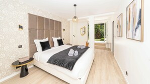A modern bedroom with a large bed, a bedside table, and a view of the garden.