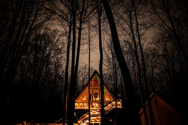 Peaceful A-Frame Retreat Tucked in the Woods l Close to Ski, Snowmobiling. Featuring a spacious deck, cozy outdoor seating and large windows to enjoy the breathtaking view--your peaceful retreat in nature awaits.