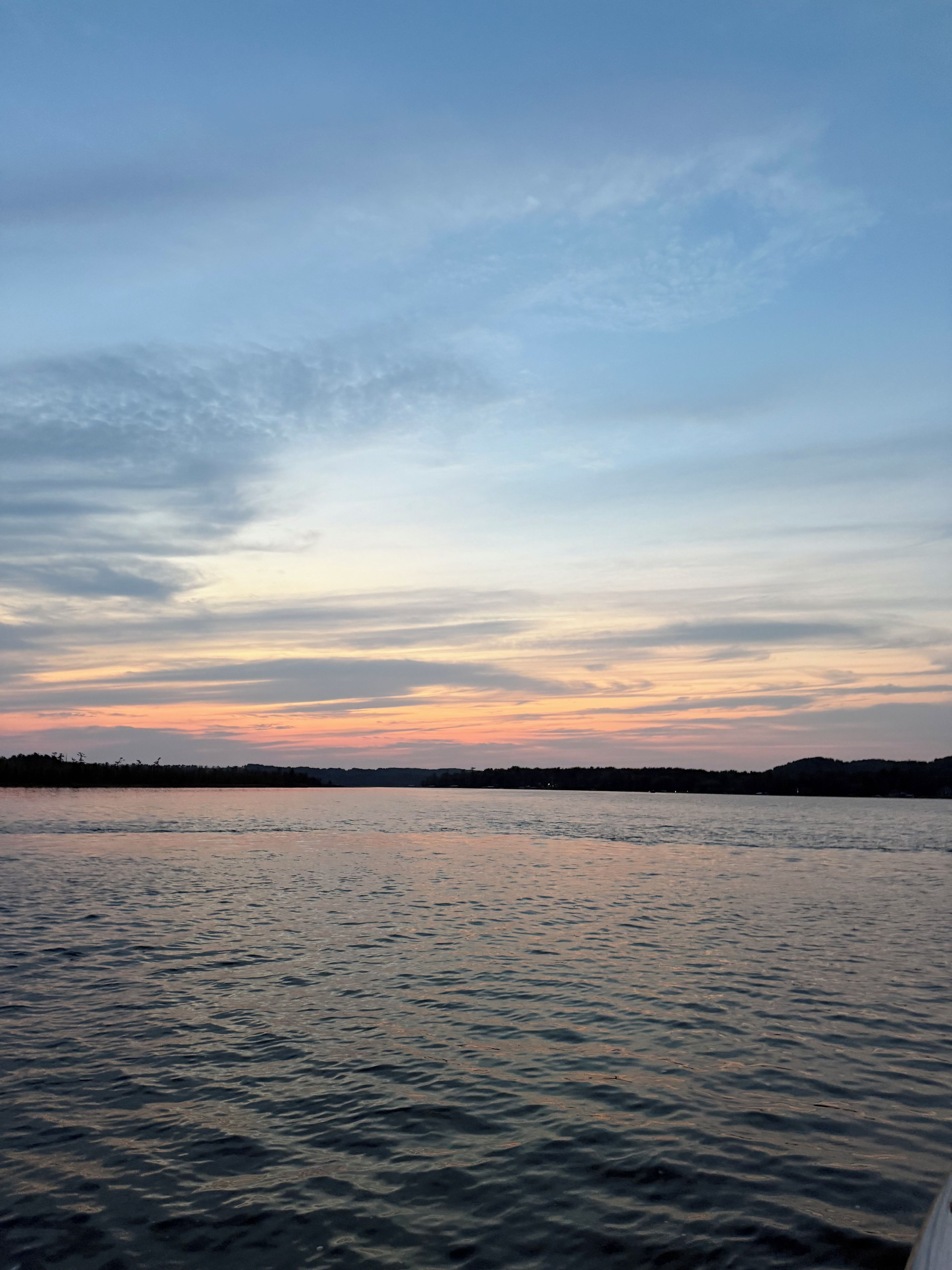 Ruhige Wasserfläche mit einer entfernten Küstenlinie und wolkenlosem Himmel.