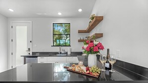 A modern kitchen with a central island, a window with a view of greenery, and a built-in wine rack.