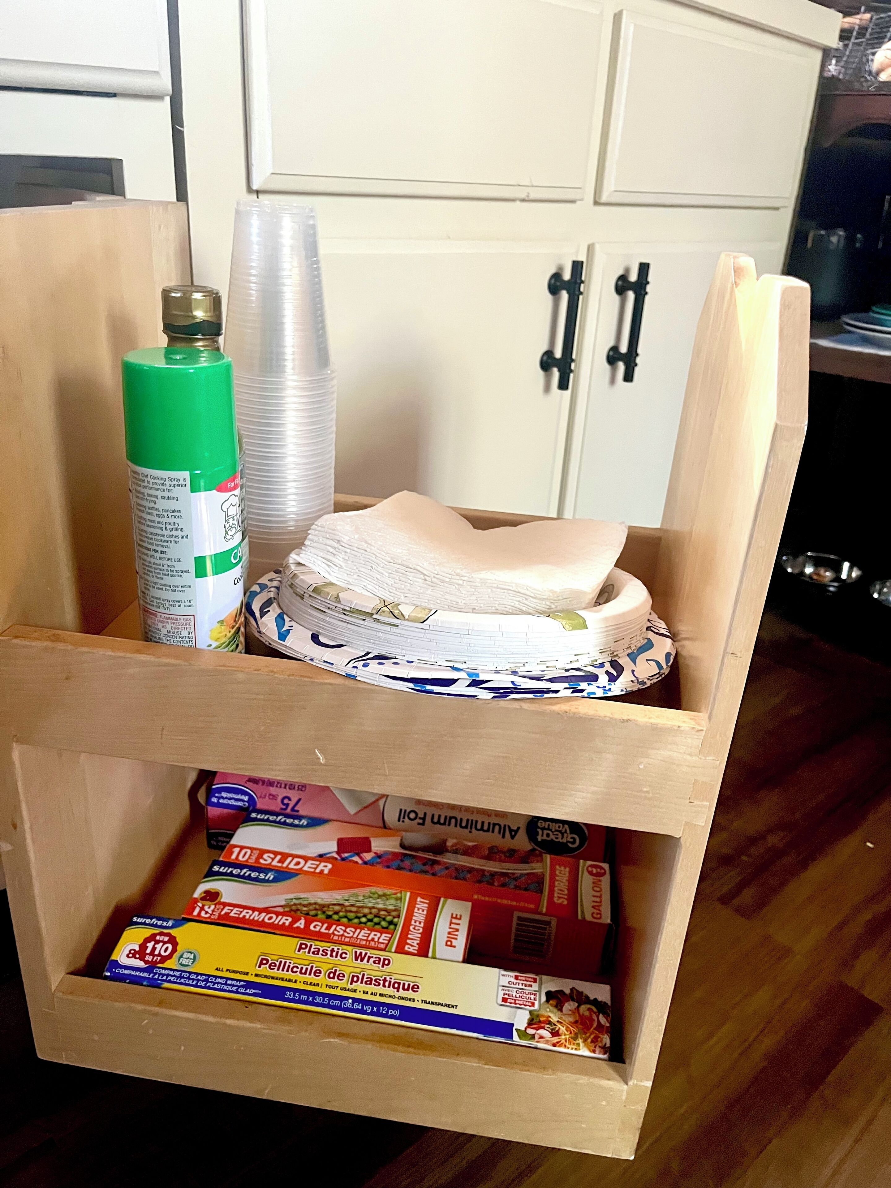 Una caja de madera con film plástico y un aerosol de cocina.