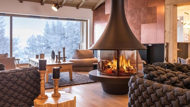 A cozy living room with a large fireplace, comfortable seating, and a view of the outdoors.