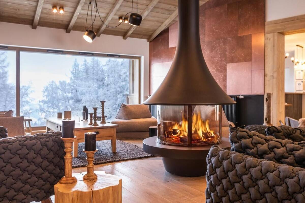Un salon chaleureux avec une grande cheminée, des sièges confortables et une vue sur l’extérieur.