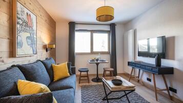 Un salon moderne avec un canapé, une table basse, un téléviseur et un tableau accroché au mur.