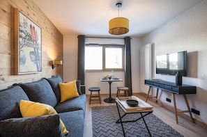 Un salon moderne avec un canapé, une table basse, un téléviseur et un tableau accroché au mur.