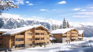 A wooden lodge with multiple balconies, set against a snowy mountain backdrop.