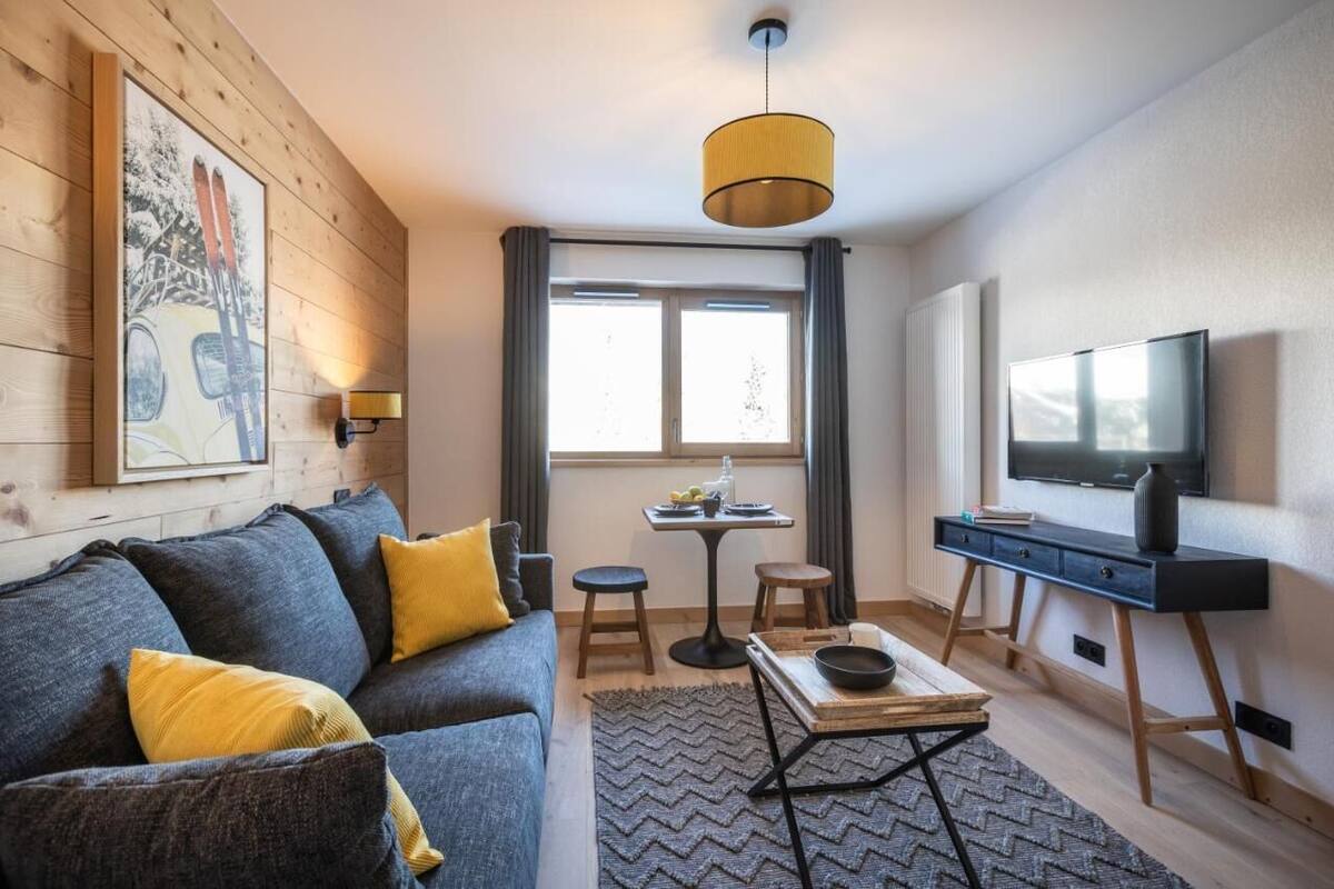 Un salon moderne avec un canapé, une table basse, un téléviseur et un tableau accroché au mur.