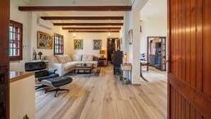 Ein geräumiges Wohnzimmer mit Holzbalkendecke, einer Couch, einem Couchtisch und einem Essbereich mit Tisch und Stühlen.