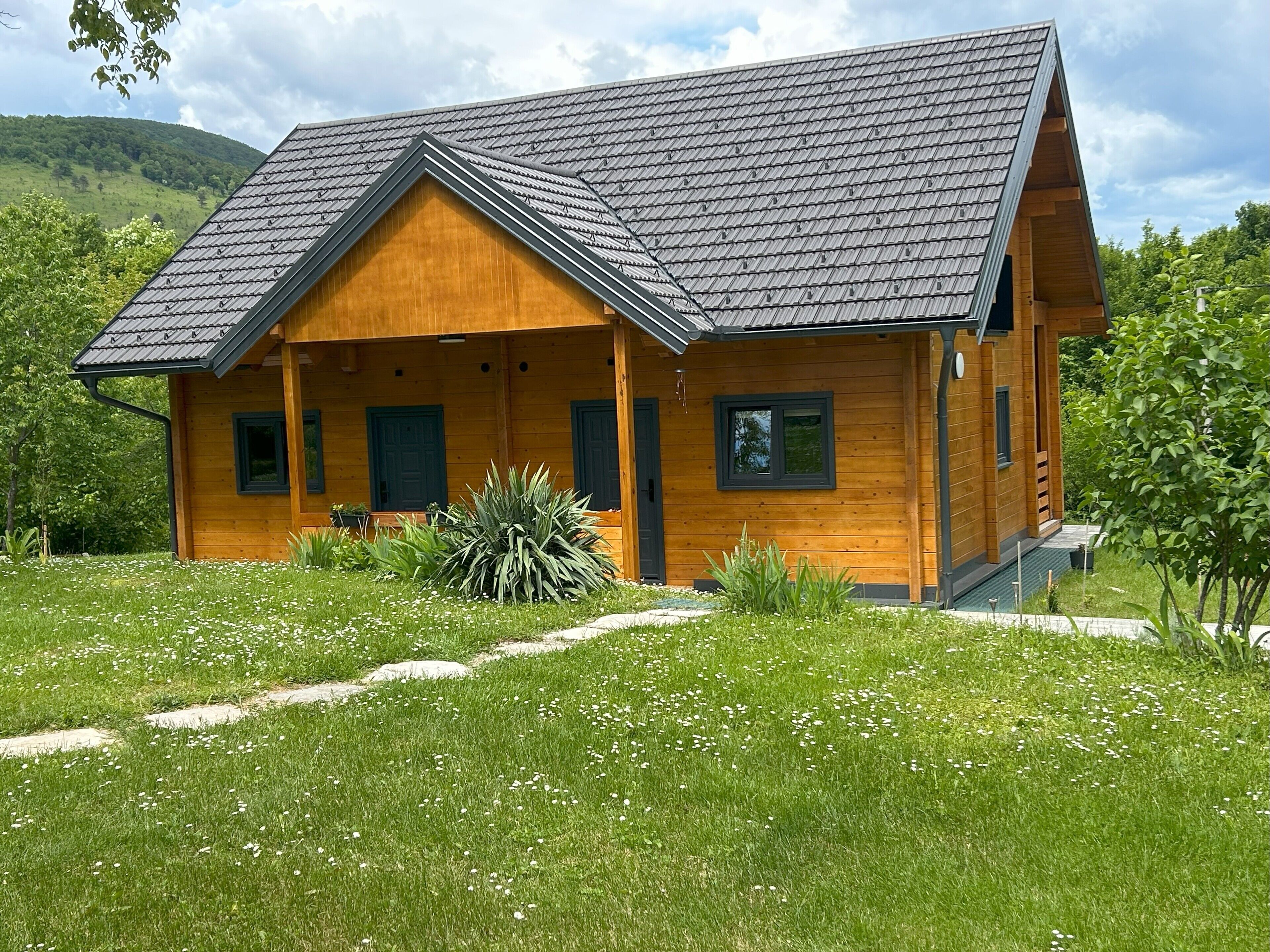 Eine Holzhütte mit geneigtem Dach, einer Veranda und einem Vorgarten.