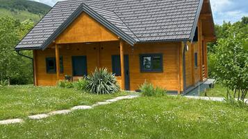 Eine Holzhütte mit geneigtem Dach, einer Veranda und einem Vorgarten.