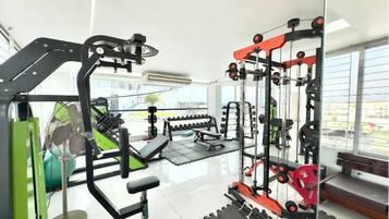 Une salle de sport équipée de divers appareils d’exercice, d’un ballon d’exercice vert et d’un banc.