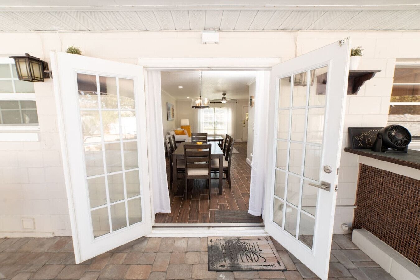 A dining area with a table and chairs, a ceiling fan, and a welcome mat.