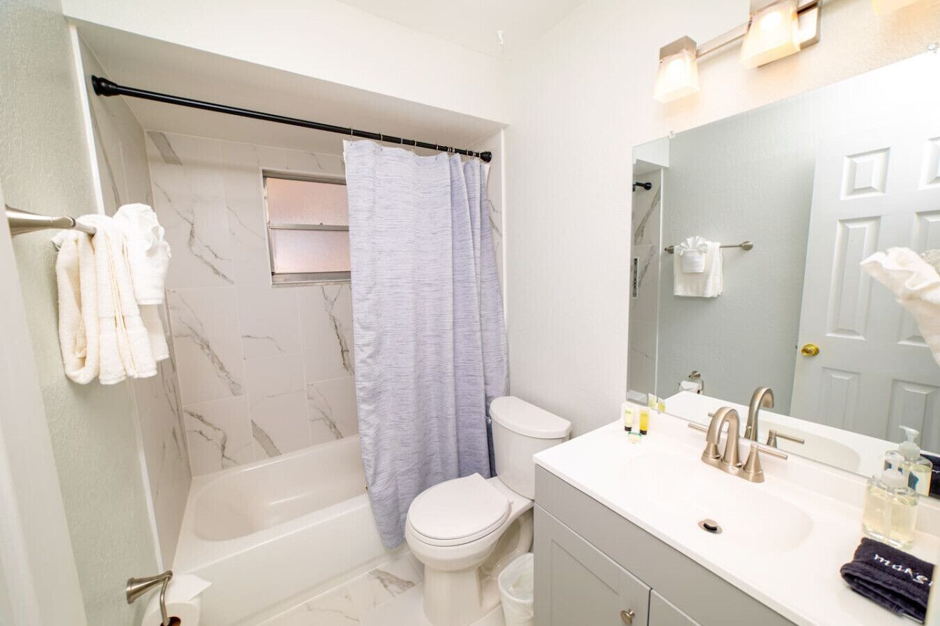 A modern bathroom with a bathtub, toilet, and vanity.