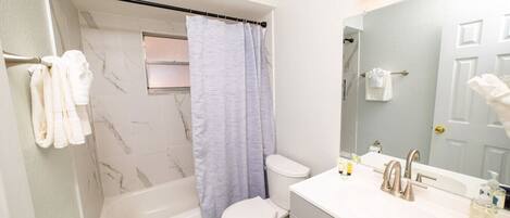 A modern bathroom with a bathtub, toilet, and vanity.