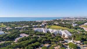 Une vue aérienne d’une ville côtière, avec ses immeubles résidentiels, ses espaces verts et une vue dégagée sur la mer.