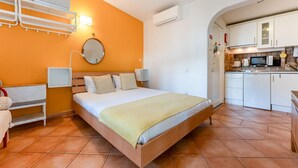 A bedroom with a bed, bedside lamps, a bedside table, a mirror, and a small cabinet.