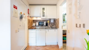 A compact kitchen with white cabinets, a microwave, a coffee maker, and a sink.