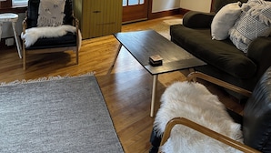 Sala de estar com sofá, poltrona, mesa de centro e ventilador de teto.