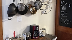 Uma cozinha com panelas penduradas, cafeteira e quadro negro com informações sobre o Wi-Fi.