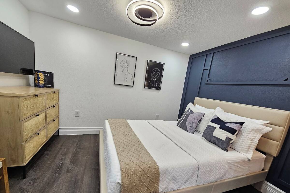 A bedroom with a bed, a dresser, and two framed artworks on the wall.
