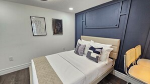 A bedroom with a bed, a chair, and two framed artworks on the wall. - Crashpads (Orlando)