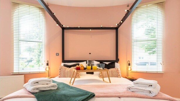 A bedroom with a bed, pillows, a bedside table, and a window.