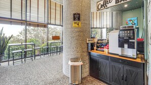 Un caffè con un cartello che indica divieto di accesso ai bambini, un cestino e un’area con tavoli e sedie.