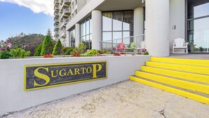 L'ingresso di un edificio con una insegna che riporta 'SugartoP' e una serie di gradini gialli che conducono all'ingresso.