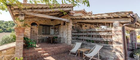 A patio with brick flooring, a pergola, and two lounge chairs.