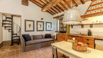 Un ambiente accogliente con una scala a chiocciola, un divano, un tavolo da pranzo con un cesto di frutta e una zona cucina.